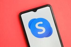 KYIV, UKRAINE - APRIL 1, 2024 Skype icon on smartphone screen on red table photo