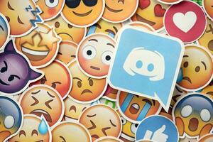KYIV, UKRAINE - APRIL 20, 2024 Discord logo and large set of stickers with Emoji yellow faces. Emoji is a pictogram or smiley embedded in text and used in electronic messages photo