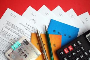 Japanese pension insurance booklets on table with yen money bills, pen and calculator on table photo