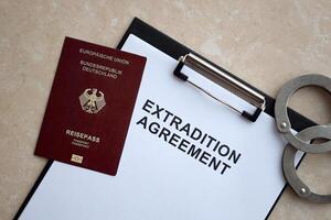 Passport of Germany and Extradition Agreement with handcuffs on table photo
