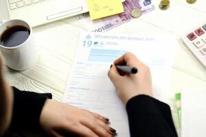 KYIV, UKRAINE - OCTOBER 31, 2023 Accountant fill french tax form 2042 income statement in end of tax period. Taxation and paperwork routine photo