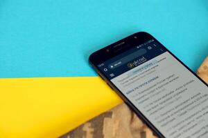 KYIV, UKRAINE - 4 MAY, 2023 Ukr Net ukrainian news portal on smartphone screen with ukrainian flag and camouflage fabric photo