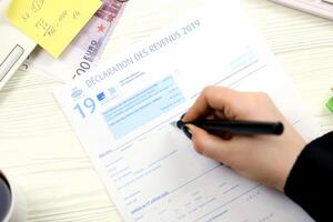 KYIV, UKRAINE - OCTOBER 31, 2023 Accountant fill french tax form 2042 income statement in end of tax period. Taxation and paperwork routine photo