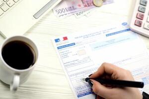 KYIV, UKRAINE - OCTOBER 31, 2023 Accountant fill french tax form 10963 Value added tax and similar taxes in end of tax period. Taxation and paperwork routine photo