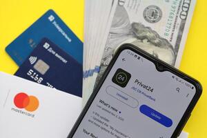 TERNOPIL, UKRAINE - JULY 7, 2023 Privatbank new banking plastic cards with money on table. Privat24 application photo