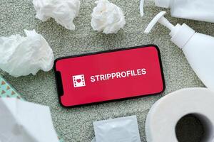 KYIV, UKRAINE - JANUARY 23, 2024 StripProfiles adult content website logo on display of iPhone 12 Pro photo