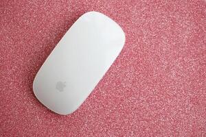 KYIV, UKRAINE - NOVEMBER 27, 2023 Apple Magic Mouse 3rd generation lies on sparkling glitter surface photo