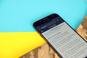 KYIV, UKRAINE - 4 MAY, 2023 Ukr Net ukrainian news portal on smartphone screen with ukrainian flag and camouflage fabric photo