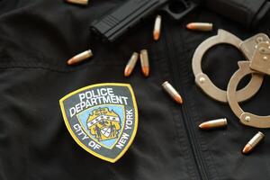 KYIV, UKRAINE - MARCH 9, 2024 US NYPD Police patch on black jacket uniform with gun, bullets and handcuffs photo