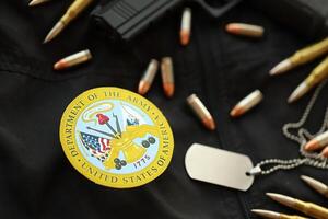 KYIV, UKRAINE - MARCH 9, 2024 US Department of Army seal on black jacket uniform with gun, bullets and dogtags photo