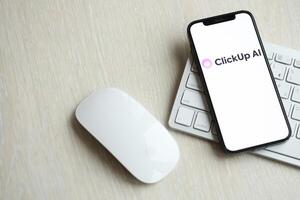 KYIV, UKRAINE - MARCH 17, 2024 ClickUp logo on iPhone display screen with apple keyboard and mouse on table photo