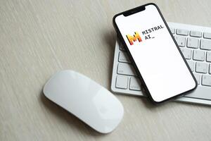 KYIV, UKRAINE - MARCH 17, 2024 Mistral AI logo on iPhone display screen with apple keyboard and mouse on table photo