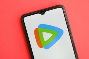 KYIV, UKRAINE - APRIL 1, 2024 Tencent WeTV icon on smartphone screen on red table photo