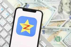 KYIV, UKRAINE - APRIL 1, 2024 Qzone icon on smartphone screen on many usd money bills photo