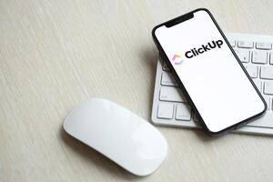 KYIV, UKRAINE - MARCH 17, 2024 ClickUp logo on iPhone display screen with apple keyboard and mouse on table photo