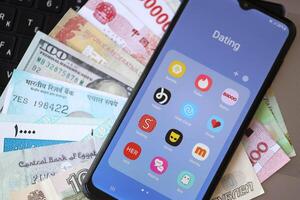 KYIV, UKRAINE - FEBRUARY 28, 2024 Dating apps icons on smartphone display and money bills photo