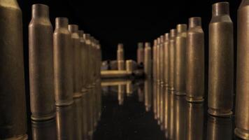 A group of spent brass cartridge casings are scattered on a black mirror surface.. The casings are arranged in various positions, some standing upright, others lying on their sides video