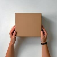 top view of female hands holding a cardboard box on a white background photo