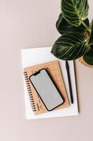 Blank path screen mobile phone with mockup on various notepads on beige background. photo