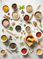 Various dry spices in small bowls and raw herbs flat lay on grey background. photo