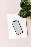 Blank path screen mobile phone with mockup on various notepads on beige background. photo