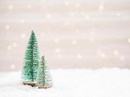 Christmas trees in the foreground in artificial snow and a blurred background with glowing garland photo