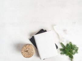 Border of various Christmas decor and notebook with blan on white textured background. Top view. Copy space photo