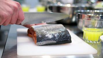 Salmon steak preparation process. Chef cooks fish steak in frying pan over black background. Cooking in restaurant. Close-up, slow motion shot video