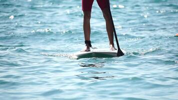 Man Sup Sea. Strong athletic man learns to paddle sup standing on board in open sea ocean on sunny day. Summer holiday vacation and travel concept. Aerial view. Slow motion video