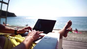 Man laptop sea. Working remotely on seashore. Happy successful man, male freelancer working on laptop on beach, relieves stress from work to restore life balance. Freelance, remote work on vacation video