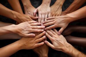 Close-up image captures group of diverse hands, each with unique skin tones, joined together in circle. Hands are stacked on top of one another, symbolizing unity, collaboration, and shared purpose photo