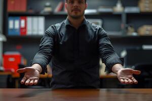 Man in a black shirt extends his hands over a table in an office photo