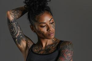 Woman with extensive tattoos posing against gray background photo