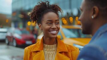 A woman in a yellow coat smiles at a man in a blue shirt, while standing in front of a car dealership. It is likely the pair are in the process of negotiating a car purchase photo