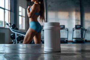 White protein powder container in a fitness gym with a woman in the background photo