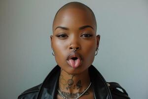 Woman with shaved head sticking out tongue in studio portrait photo
