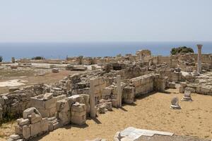 The extensive ruins of Kourion, with columns and remnants of ancient structures, set against the Mediterranean Sea. photo
