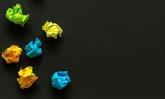 crumpled sheets of colored paper on a dark background, failed attempts, motivation concept photo
