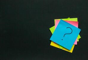 stack of stickers with questions on a black board, questions and idea concept photo