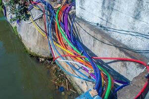 lots of messy colorful cables in the gutter consisting of high voltage telecommunications and electrical cables photo