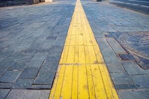 Bright yellow tactile paving for the visually impaired on the sidewalk. photo