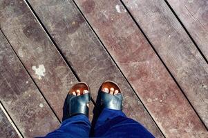 Standing on vintage gray wooden board floor. Looking down on the feet. wearing sandal. photo