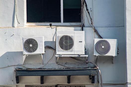 three air conditioner condensers or blowers installed on the outside of the building photo