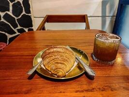a plate of croissant bread and a glass of tea or beer or whiskey served on a wooden table in a luxury cafe or restaurant photo
