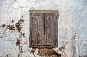 old brittle and dull wooden windows and grunge on dull white walls and corrosion looking bricks that are peeling and cracking photo
