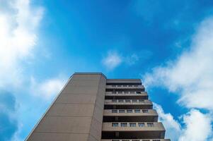 a tall building with a cloudy blue sky in the background. a hotel or inn or apartment photo