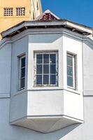 Clean white corner bay windows on beach house, contrasting with deep blue sky. Belanda colonialism Building era in Indonesia. photo