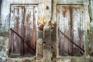 old brittle and dull wooden windows and grunge on dull white walls and corrosion looking bricks that are peeling and cracking photo