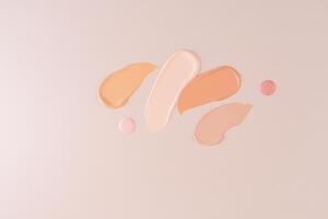 samples of liquid foundation powder in different tones and two round drops of cream on a beige background. top view. cosmetic design photo