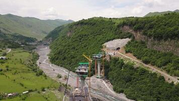 Kazbegi, Georgia - 7th july, 2024- aerial view cranes and bridge foundation pillars on construction site of new highway road project built by chinese builders.Avalanche bypass tunnel.Tbillisi - Lars video